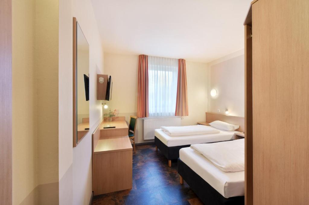 a hotel room with two beds and a mirror at meinHotel in Hamburg