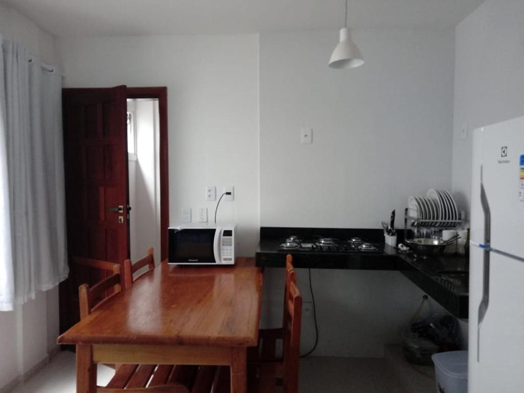 cocina con mesa de madera y microondas en Apartamentos Juliel, en Morro de São Paulo