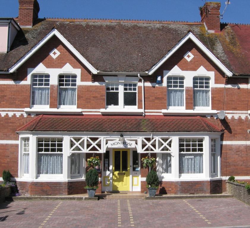 a red brick building with a yellow door at Montrose Guest House in Minehead