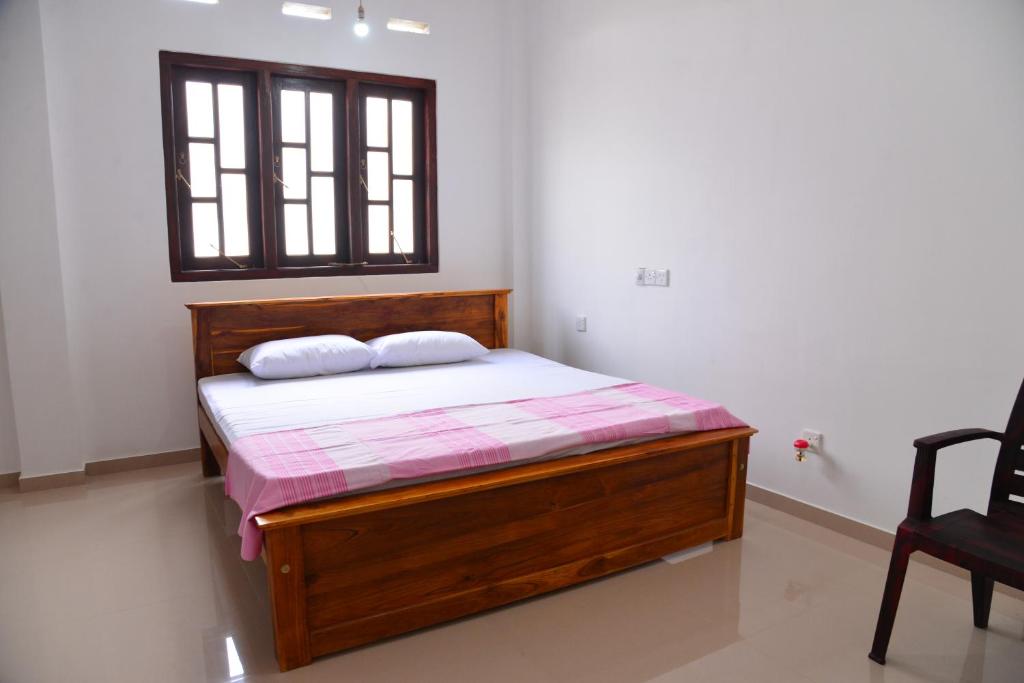 una camera con letto in legno e finestra di Roshan's Guest House a Hikkaduwa