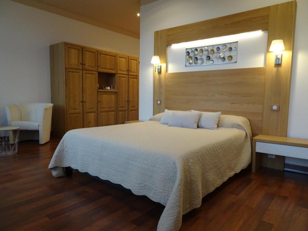 a bedroom with a large bed with a wooden headboard at Hôtel la Guimbarde in Morteau