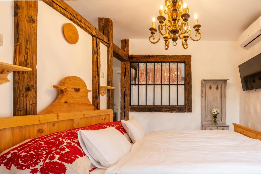 a bedroom with a bed and a chandelier at Tenkes Fogadó és Vendégház Harkány in Harkány