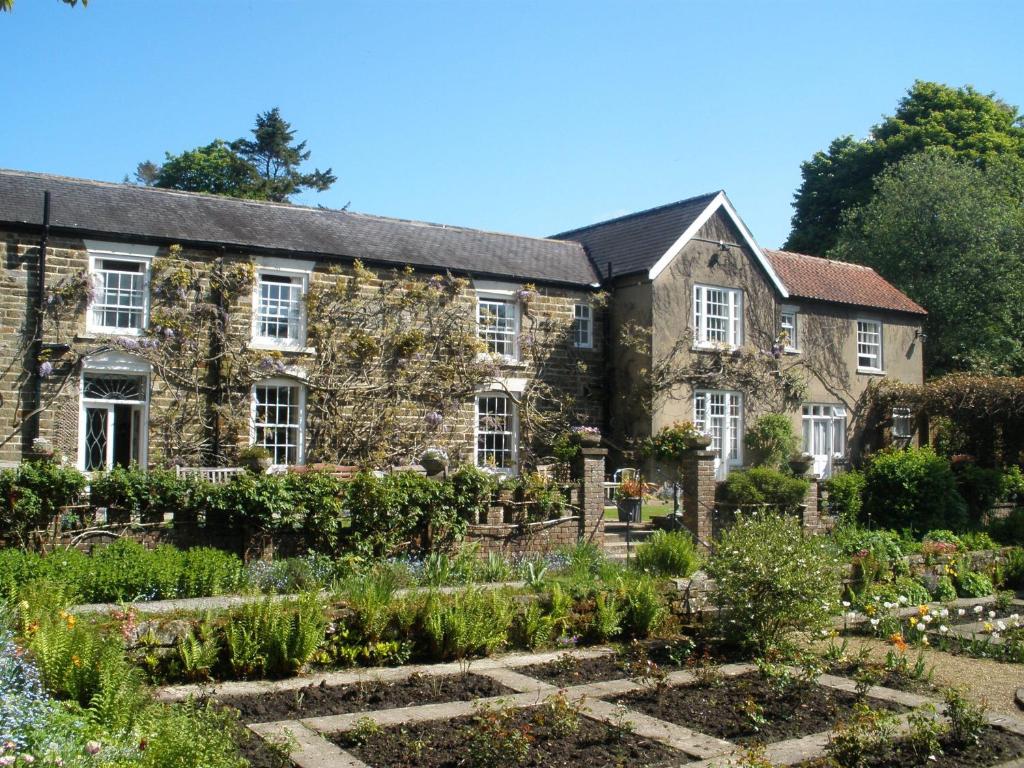 una antigua casa de piedra con un jardín en el primer plano en Lastingham Grange, en Lastingham