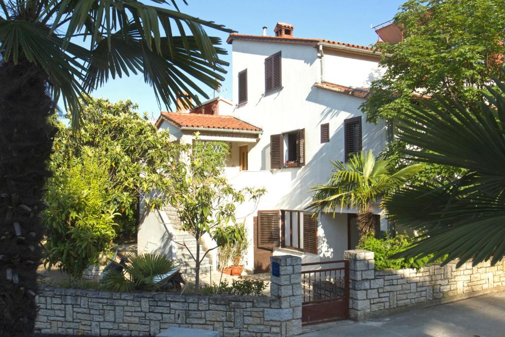 a white house with a fence in front of it at Apartments Mladenka in Poreč