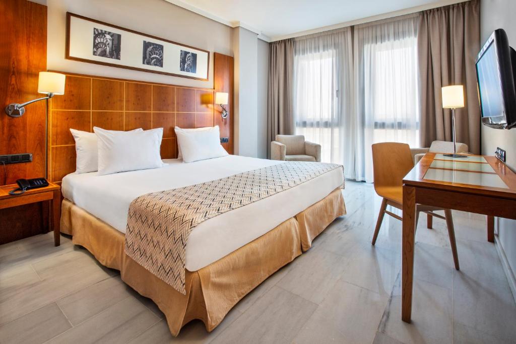 a hotel room with a large bed and a desk at Exe Ciudad de Córdoba in Córdoba