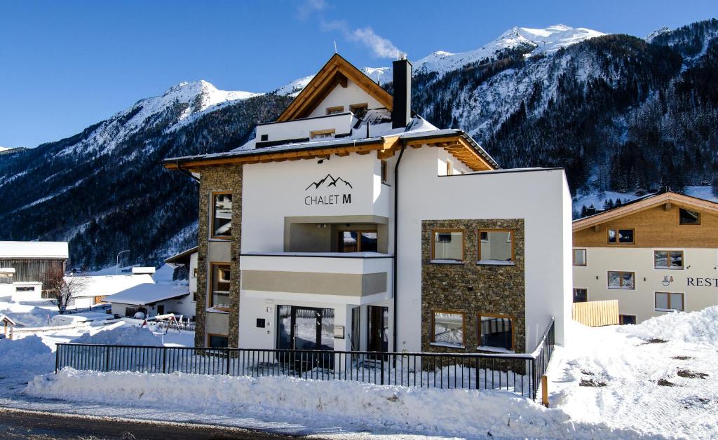 a building in the snow with mountains in the background at Chalet M in Ischgl