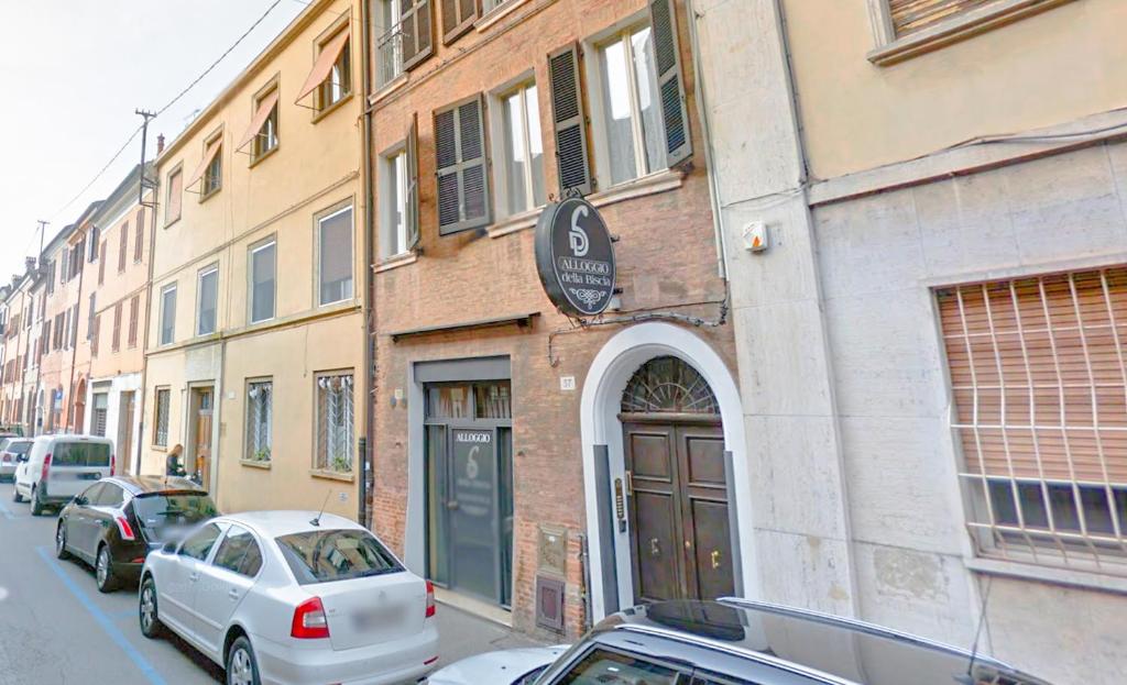 un edificio con coches aparcados al lado de una calle en Locanda Della Biscia, en Ferrara