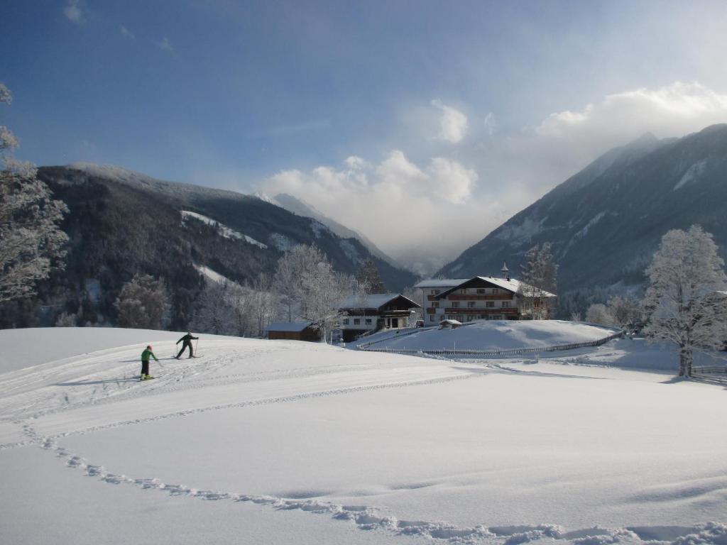 two people are skiing down a snow covered slope at Pension Stammerhof in Schladming