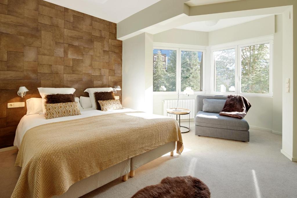 a bedroom with a bed and a chair and windows at Amitges by FeelFree Rentals in Baqueira-Beret