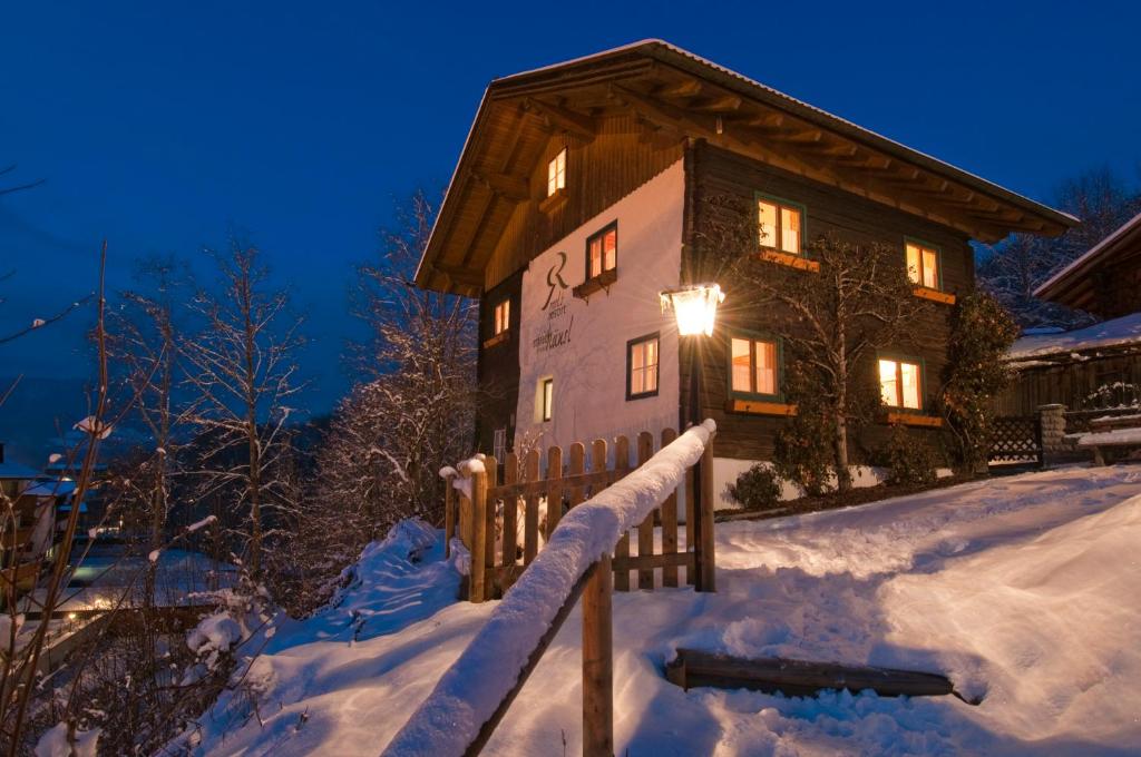 Una casa con una cerca en la nieve por la noche en Ferienhaus/Chalet Schneiderhäusl, en Flachau
