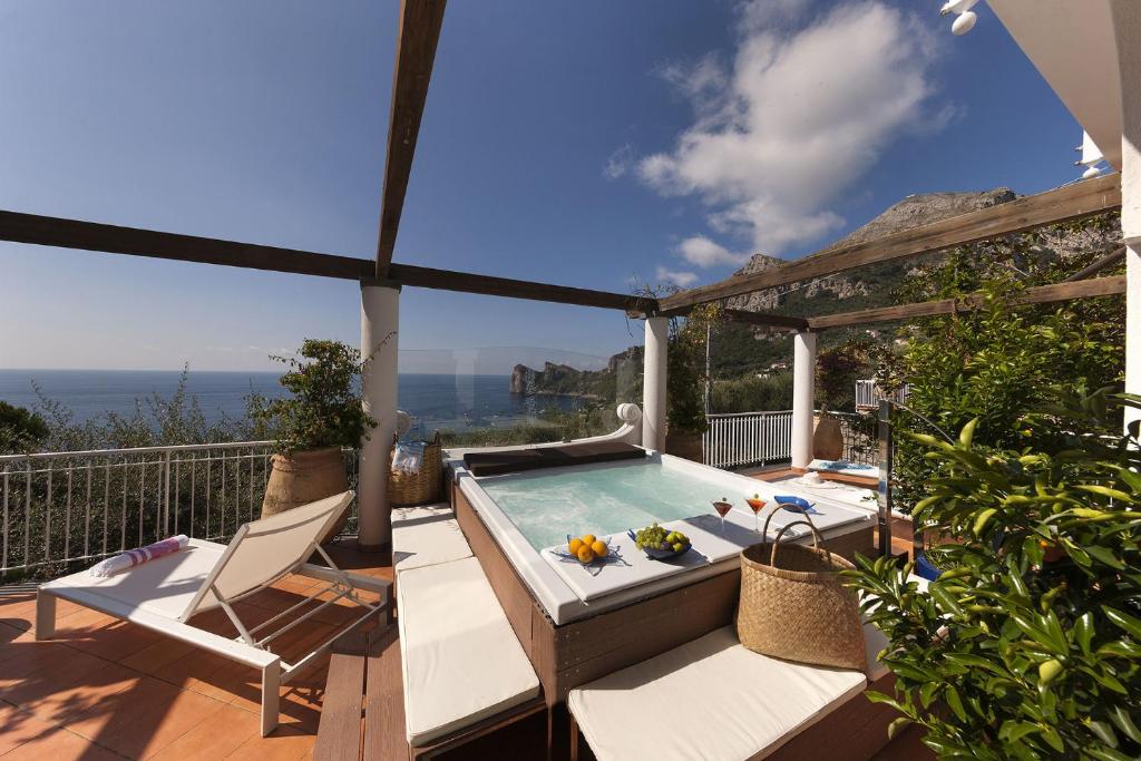 un patio con piscina e una terrazza con sedie. di AMORE RENTALS - Villa Giove a Nerano