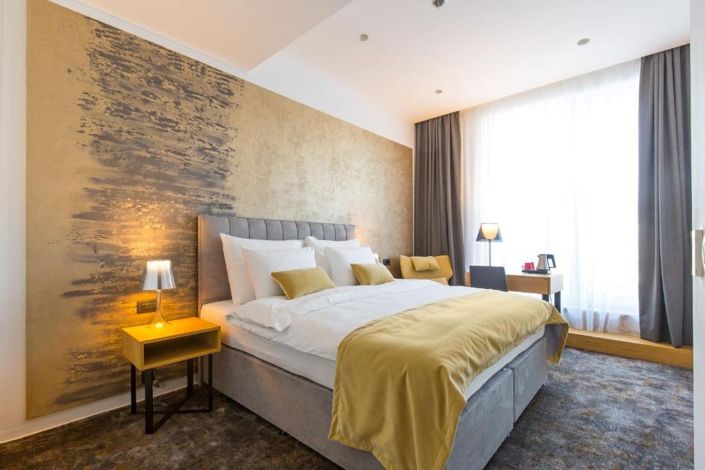 a bedroom with a large bed and a painting on the wall at Boutique Hotel Museum in Belgrade