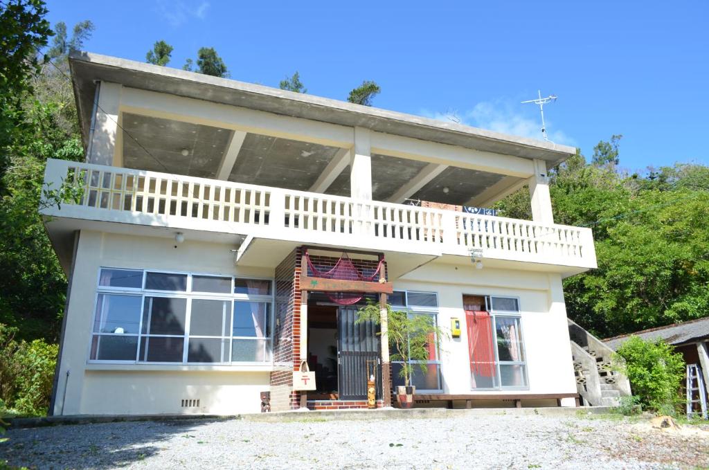 名護市にあるbackpackers guesthouse Borderのバルコニー付きのホワイトハウスです。