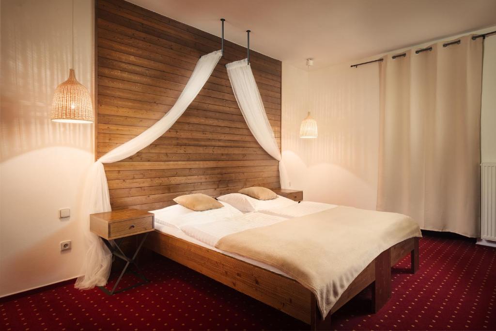 a bedroom with a large bed with a wooden headboard at Hotel Sharingham in Brno