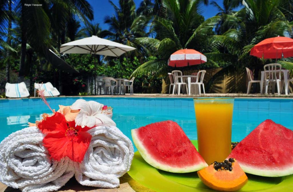 a plate of watermelons and a drink next to a pool at Vale Verde Coroa Vermelha in Santa Cruz Cabrália