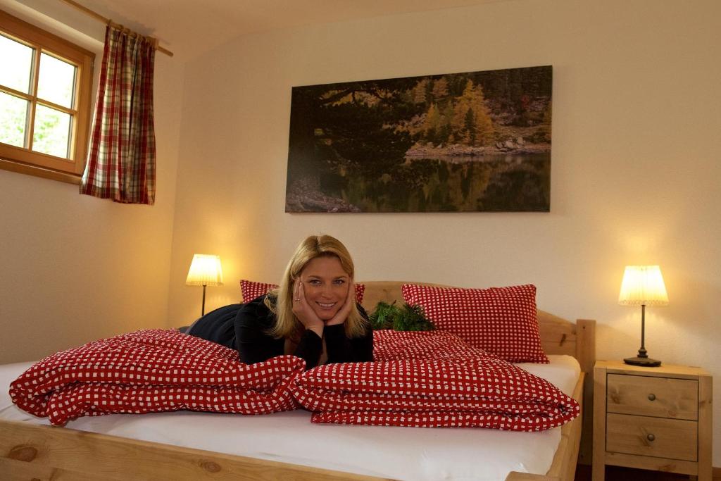 a woman laying on a bed with pillows at Rainbachhütte-Waldgut Granig in Glödnitz