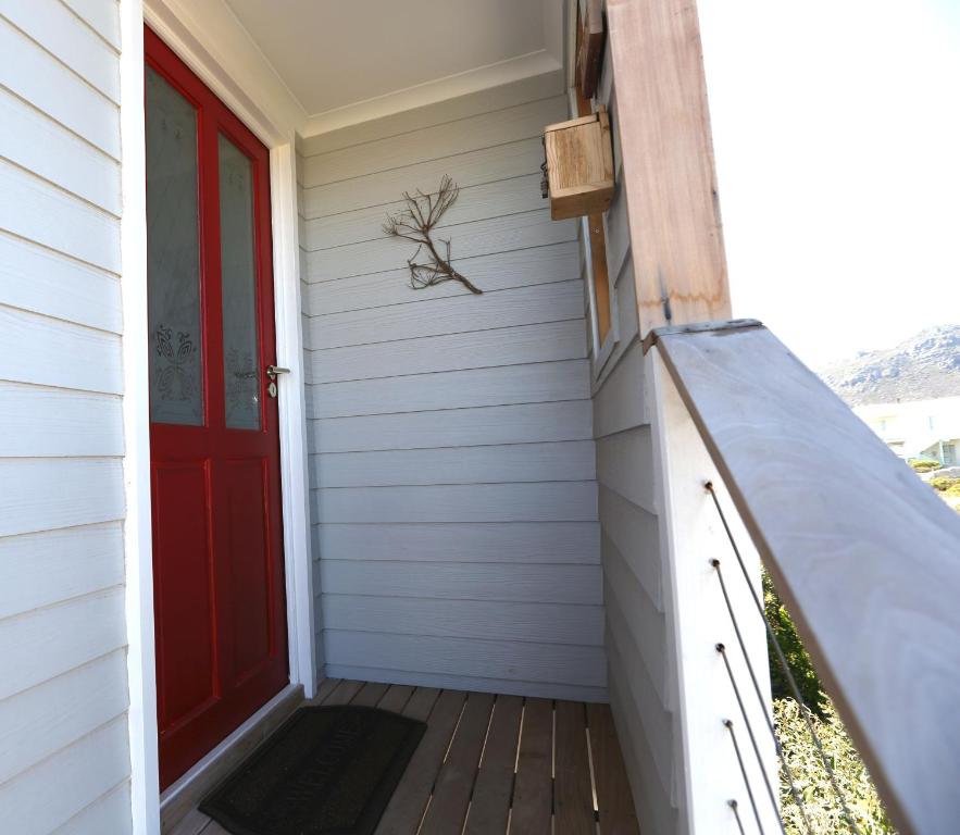 - une porte rouge sur une maison avec terrasse couverte dans l'établissement Reddoor Studio, à Pringle Bay