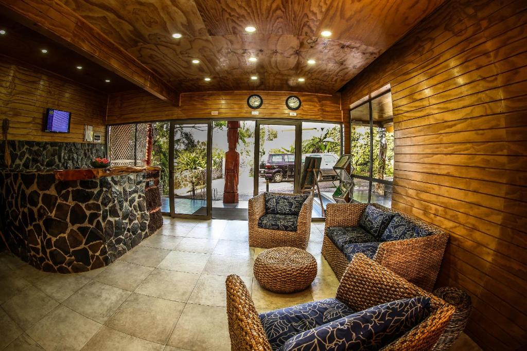 Easter Island Ecolodge في هانجا روا: غرفة معيشة مع جدران وكراسي خشبية وبار