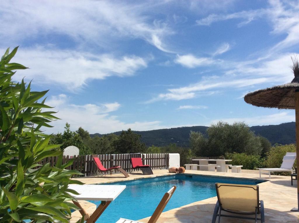 a swimming pool with chairs and a umbrella at Villa Can Mestreso Suite Ibiza in Sant Joan de Labritja