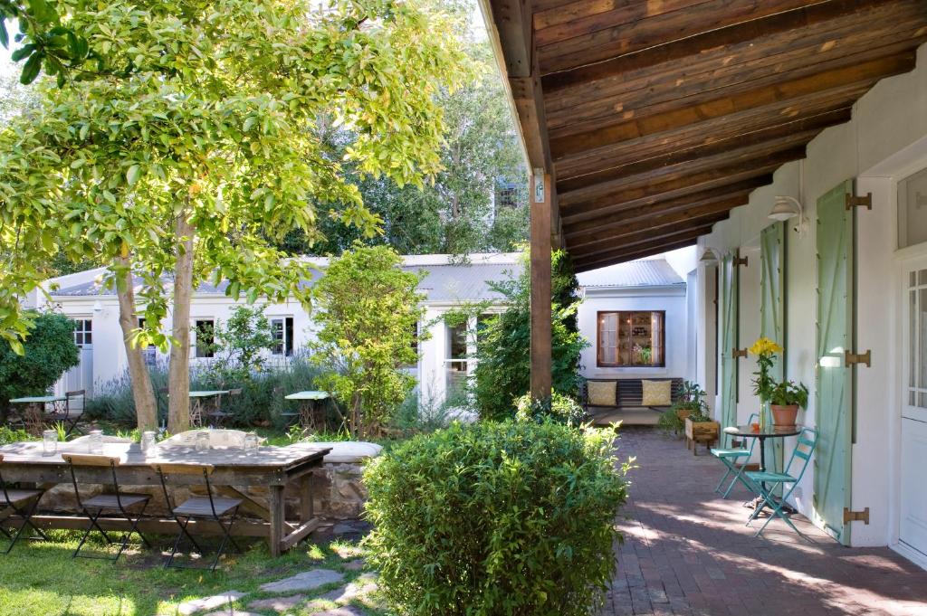 eine Veranda eines Hauses mit einem Tisch und einem Kamin in der Unterkunft La Grenadine in Kapstadt