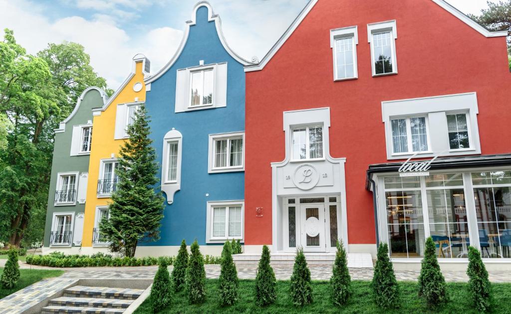 a row of colorful houses with trees in front at Madame L & SPA in Svetlogorsk