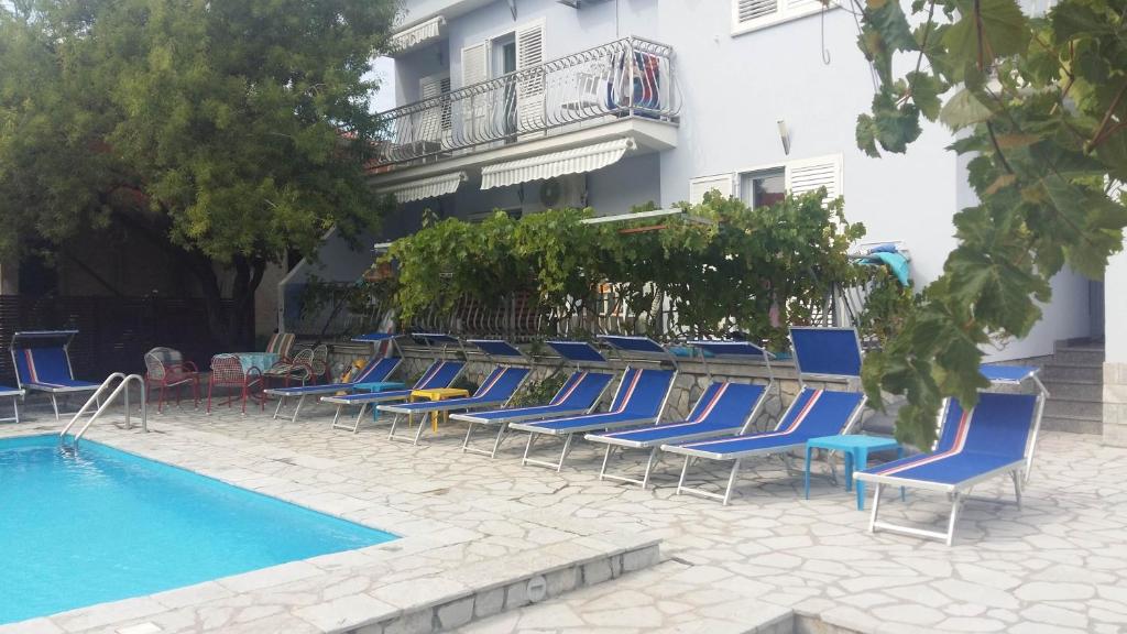 uma fila de cadeiras e uma piscina ao lado de um edifício em Apartments Jerine em Tribunj