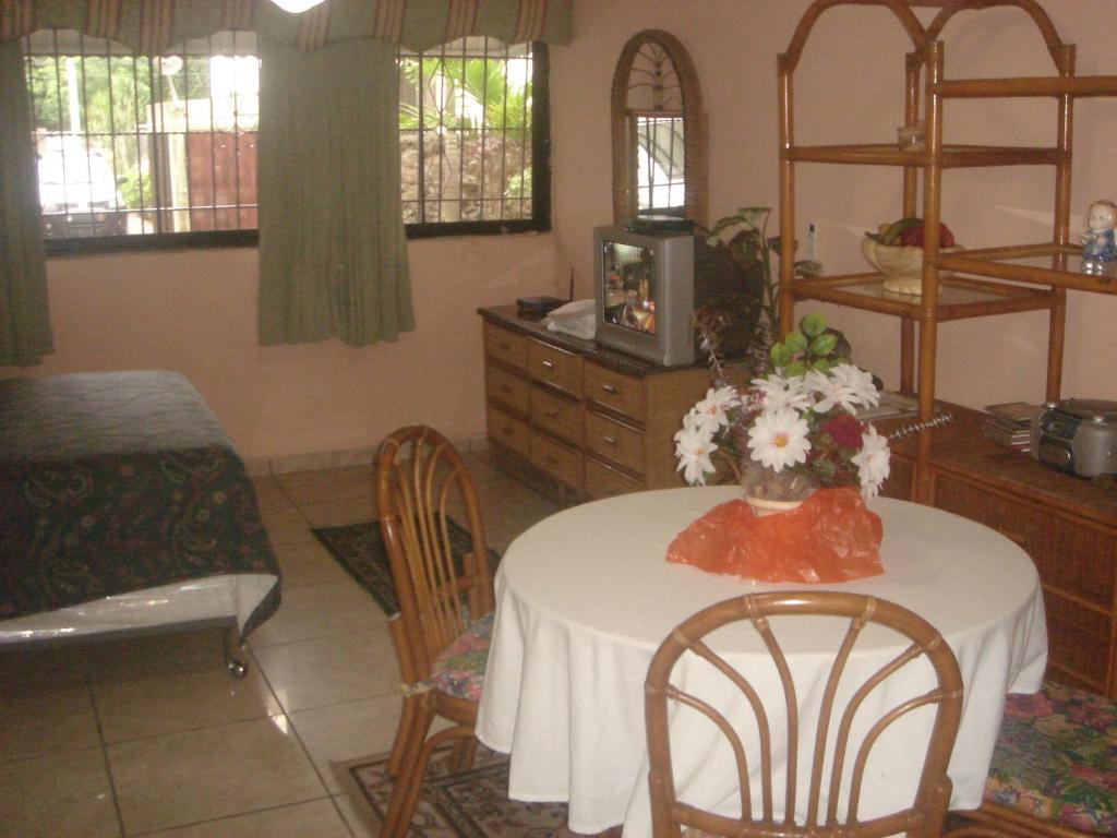 una habitación con una mesa y sillas con un jarrón de flores en Dre Broeders Apartments Juan Dolio, en Juan Dolio
