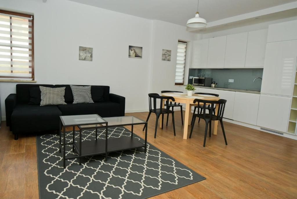 a living room with a black couch and a table at Poduszka Apartamenty Zdrojowe in Nałęczów