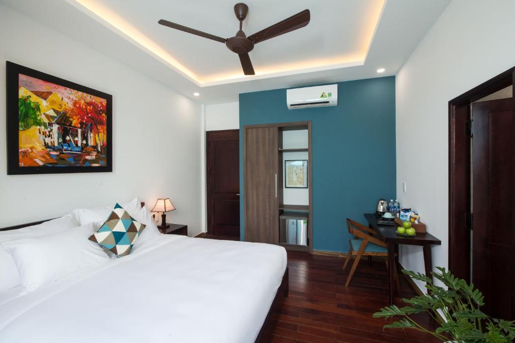 a bedroom with a white bed and a blue wall at La An Homestay in Hoi An