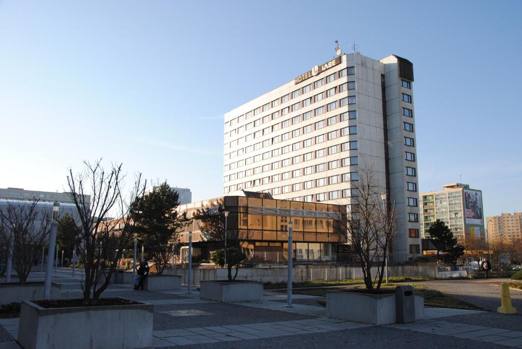 un grand bâtiment avec des arbres devant lui dans l'établissement Hotel Labe, à Pardubice