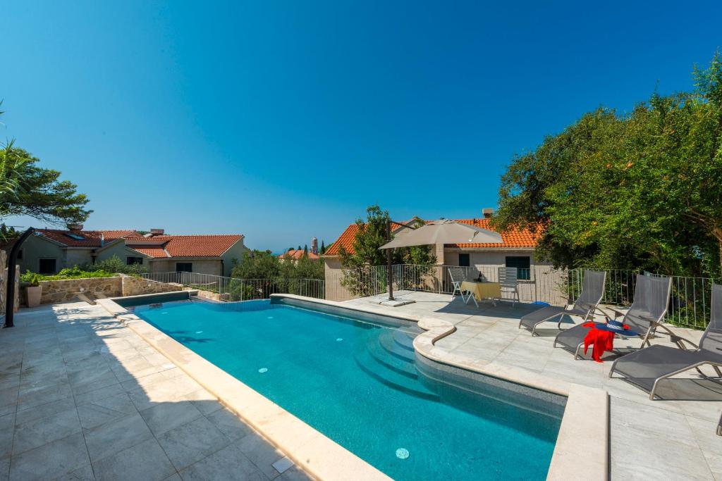 a swimming pool in a yard with chairs and a house at Apartment Obradovic in Cavtat