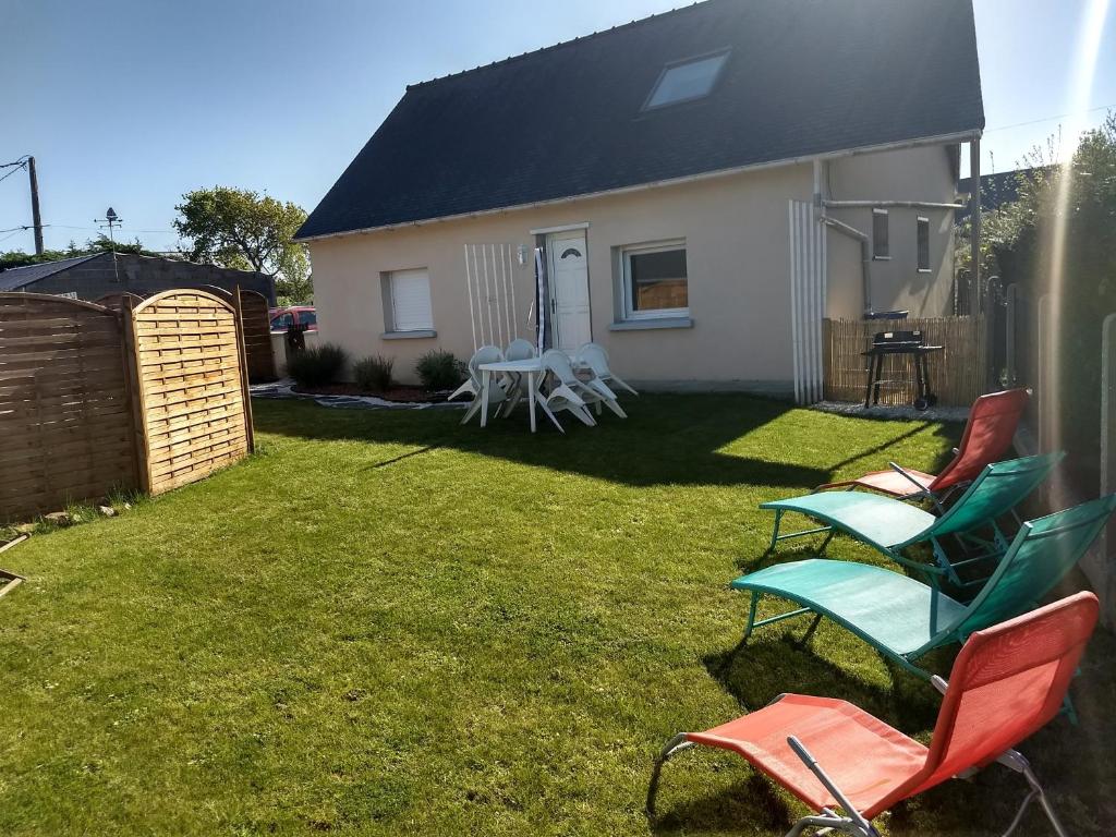 a yard with chairs and a table and a house at Gite d' angel in Kermaria-Sulard