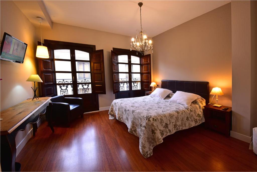a bedroom with a bed and a desk and windows at Salamanca Centro Apartamentos in Salamanca
