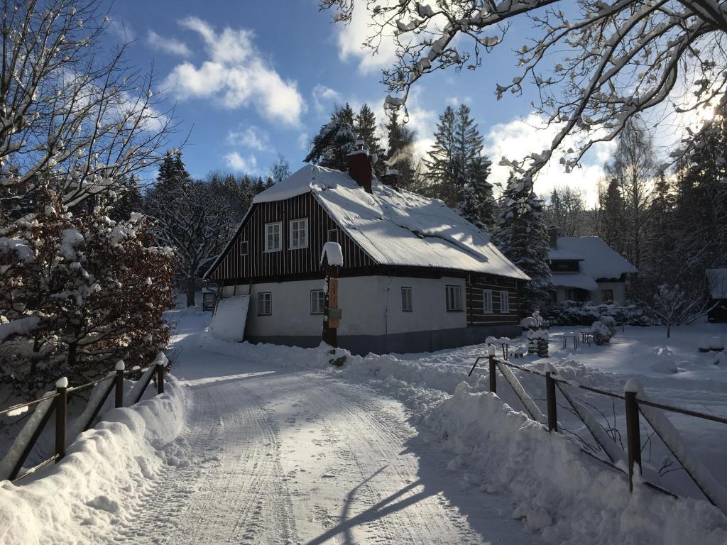 a house is covered in snow with a fence at Rodinná chalupa jen pro sebe in Harrachov