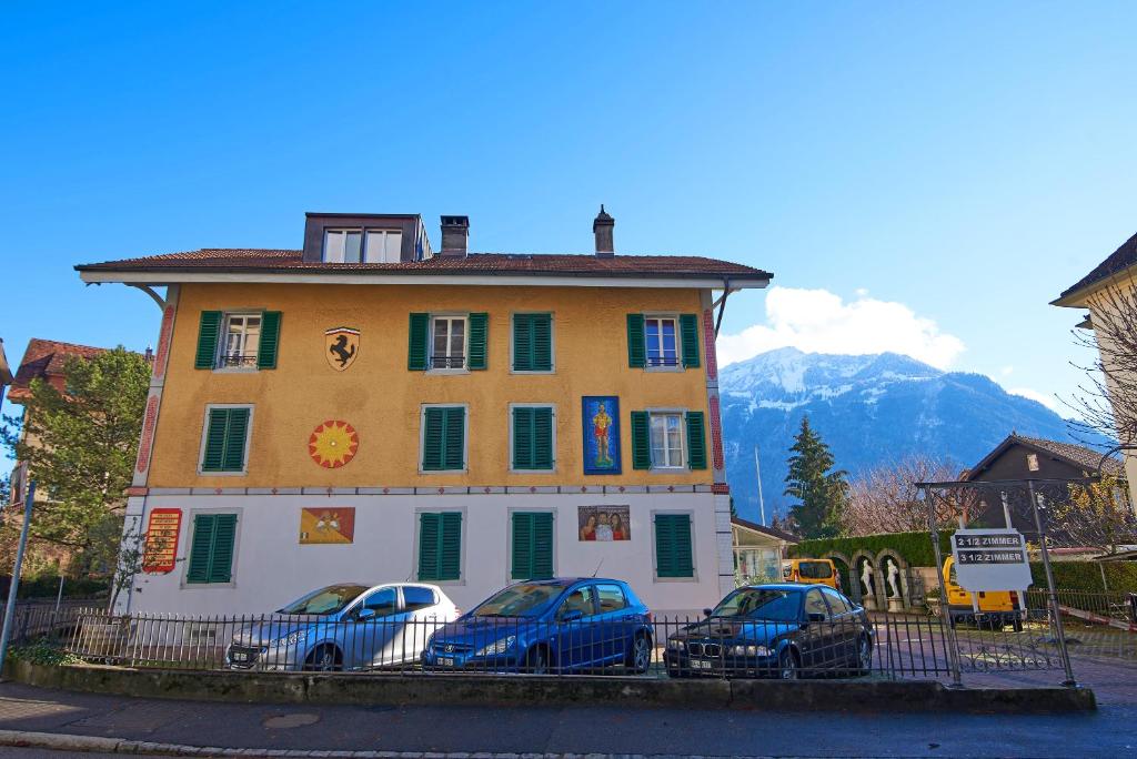 a building with three cars parked in front of it at Central Park Holiday apartment in Interlaken