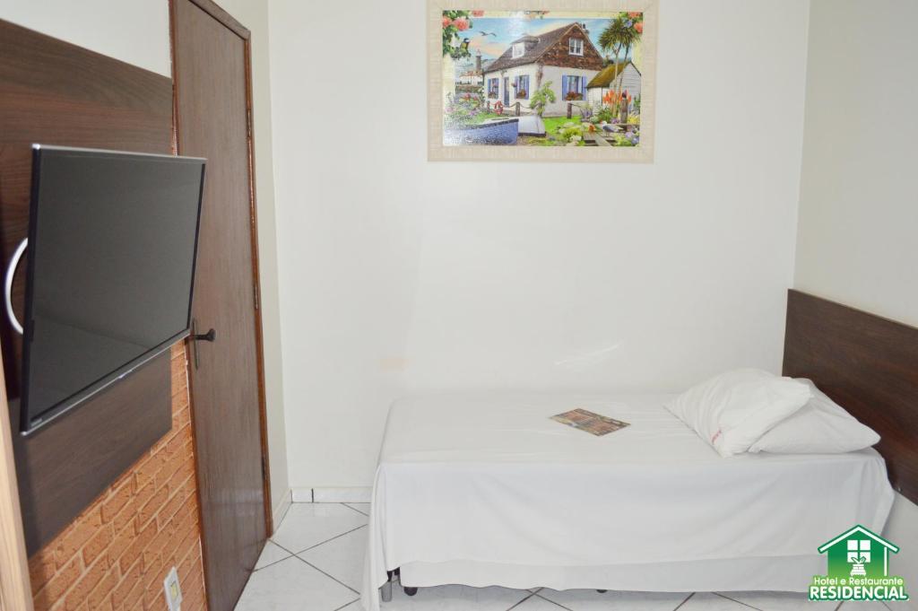 1 dormitorio pequeño con 1 cama y una foto en la pared en Hotel e Restaurante Residencial, en Montes Claros