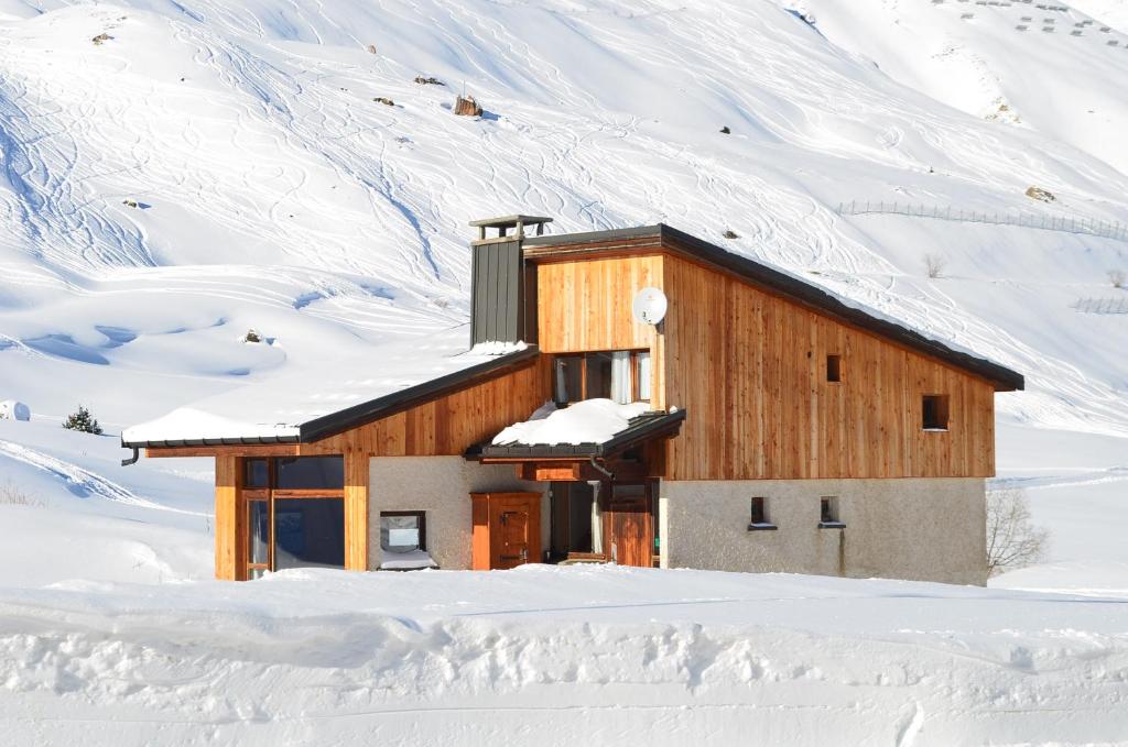 une cabane en bois dans la neige avec une montagne enneigée dans l'établissement Chalet Reymond Pre du lac, à Tignes