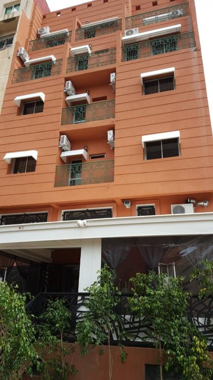 a tall orange building with trees in front of it at Hotel VELSATIS in Beni Mellal