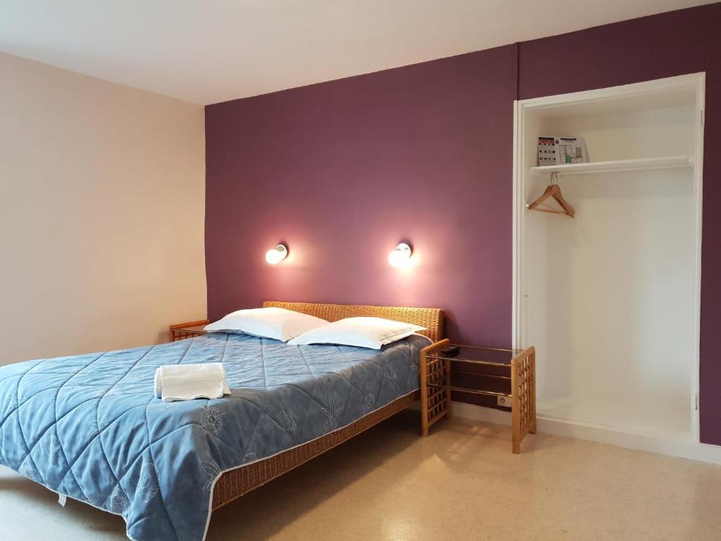 1 dormitorio con 1 cama con pared morada en Hôtel Ecu de france, en Secondigny