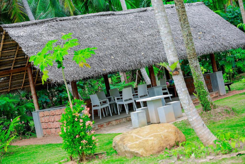 a restaurant with a table and chairs and a thatch roof at Kurumba Villas in Bentota