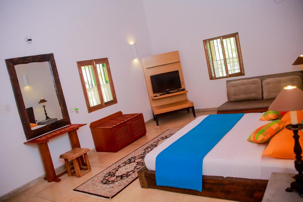 a bedroom with a large bed and a mirror at Kurumba Villas in Bentota