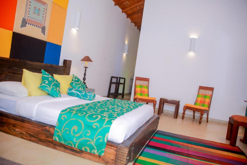 a bedroom with a bed and chairs in a room at Kurumba Villas in Bentota