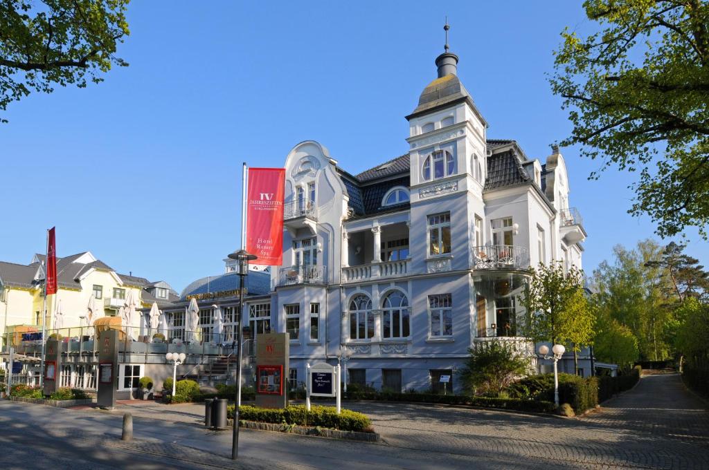 ein großes weißes Gebäude mit einem roten Schild darauf in der Unterkunft Hotel Vier Jahreszeiten Kühlungsborn in Kühlungsborn