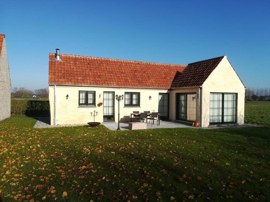 een wit huis met een rood dak en een tuin bij Vakantiehuis Schardauw in Damme