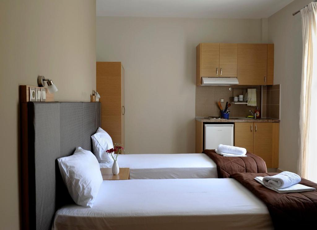 a hotel room with two beds and a kitchen at Niriides Studios and Apartments in Paralia Katerinis