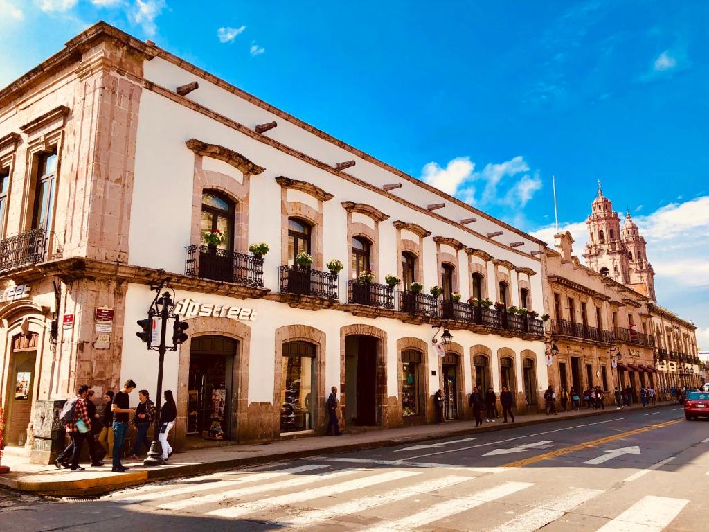 Un bâtiment au coin d'une rue avec des gens debout à l'extérieur dans l'établissement Hotel Herencia By Hosting House, à Morelia