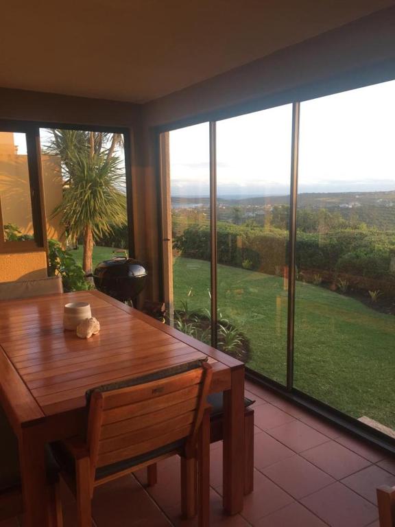 a dining room with a wooden table and large windows at 20A Castleton in Plettenberg Bay