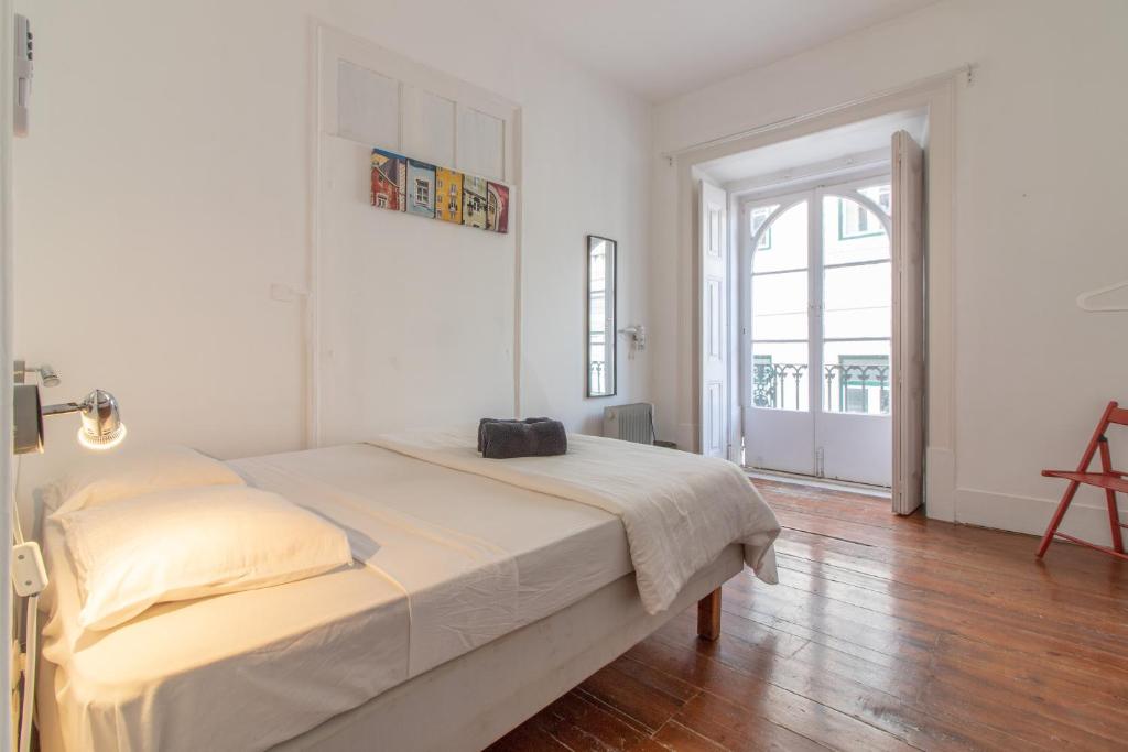 a white bedroom with a bed and a large window at Party Zone in Lisbon