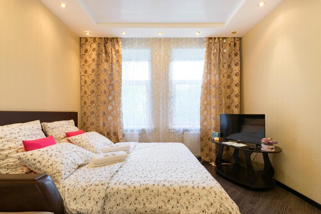 a bedroom with a bed and a tv and a window at Apartment on Bolshaya Nizhegorodskaya Бесконтактное Заселение in Vladimir