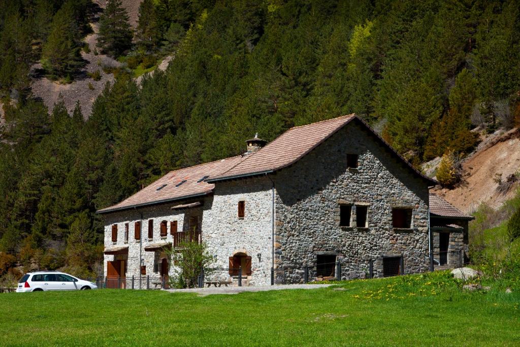 ein großes Steingebäude mit einem daneben geparkt in der Unterkunft Refugio de Bujaruelo in Torla-Ordesa